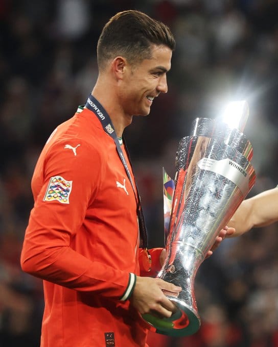 Kapten Portugal, Cristiano Ronaldo, tersenyum bangga sambil mengangkat trofi UEFA Nations League 2025.