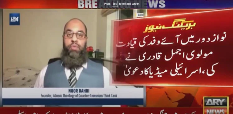 Cuplikan layar siaran berita televisi Pakistan, menampilkan seorang pria dengan janggut berbicara di sisi kiri dan panel berita utama di sisi kanan yang menampilkan teks besar dalam bahasa Urdu. Latar belakang menunjukkan logo saluran berita "ARY NEWS".