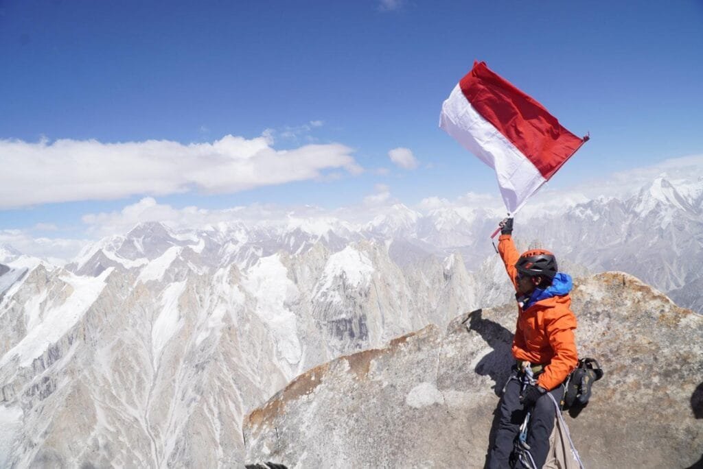Tim pemanjat tebing IBEX berfoto dengan latar belakang bendera Merah Putih dan spanduk HUT ke-80 RI di puncak Trango Tower, Pakistan, sebagai bagian dari Ekspedisi Trango Tower Indonesia
